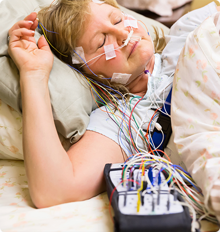 Woman hooked up to various sensors being monitored during her sleep study.