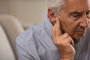 Side view of senior man with symptom of hearing loss.