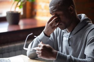 African student or worker sitting at table taking off eyeglasses massaging nose bridge suffering from dry eyes or eyestrain after long computer usage, modern tech negative impact on the health concept