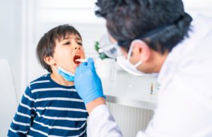 Doctor examining a young boy's throat