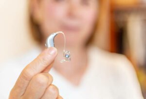 Woman holding hearing aid next to the ear