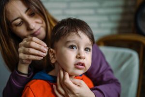 Mother helping her son with his Hearing Aid