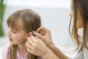 Hearing Aid specialist fitting the device in child's ear