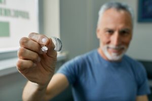 Senior man holding hearing aid in hand