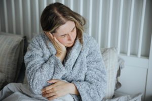 A young woman is holding her ear because she is experiencing an earache.