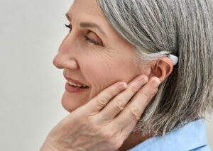 A senior woman enjoys sound using hearing aids to help reduce the impact of hearing loss on her life with hearing aids.