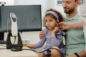 A hearing loss specialist is conducting a hearing test for a child and offering a consultation to the parent at the clinic.