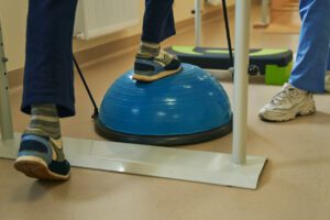 A middle-aged patient is exercising in a neurological rehabilitation facility to improve balance disorders.