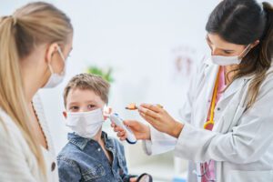 A little boy is having his ear examined by a female doctor during a visit for treatment of his ear infection.