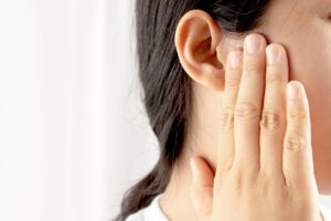 Young woman suffering from earache caused by an ear infection.